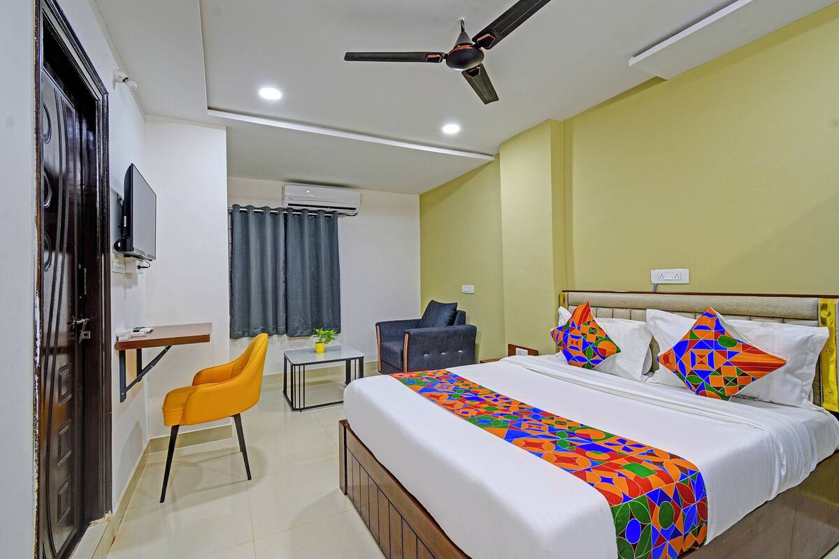 A hotel room with a bed, a desk, a chair, and a ceiling fan.