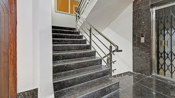 A staircase with black marble steps and metal railings, leading to a door with a security keypad. - Fabhotel Dolce Vita Grand (Hyderabad)