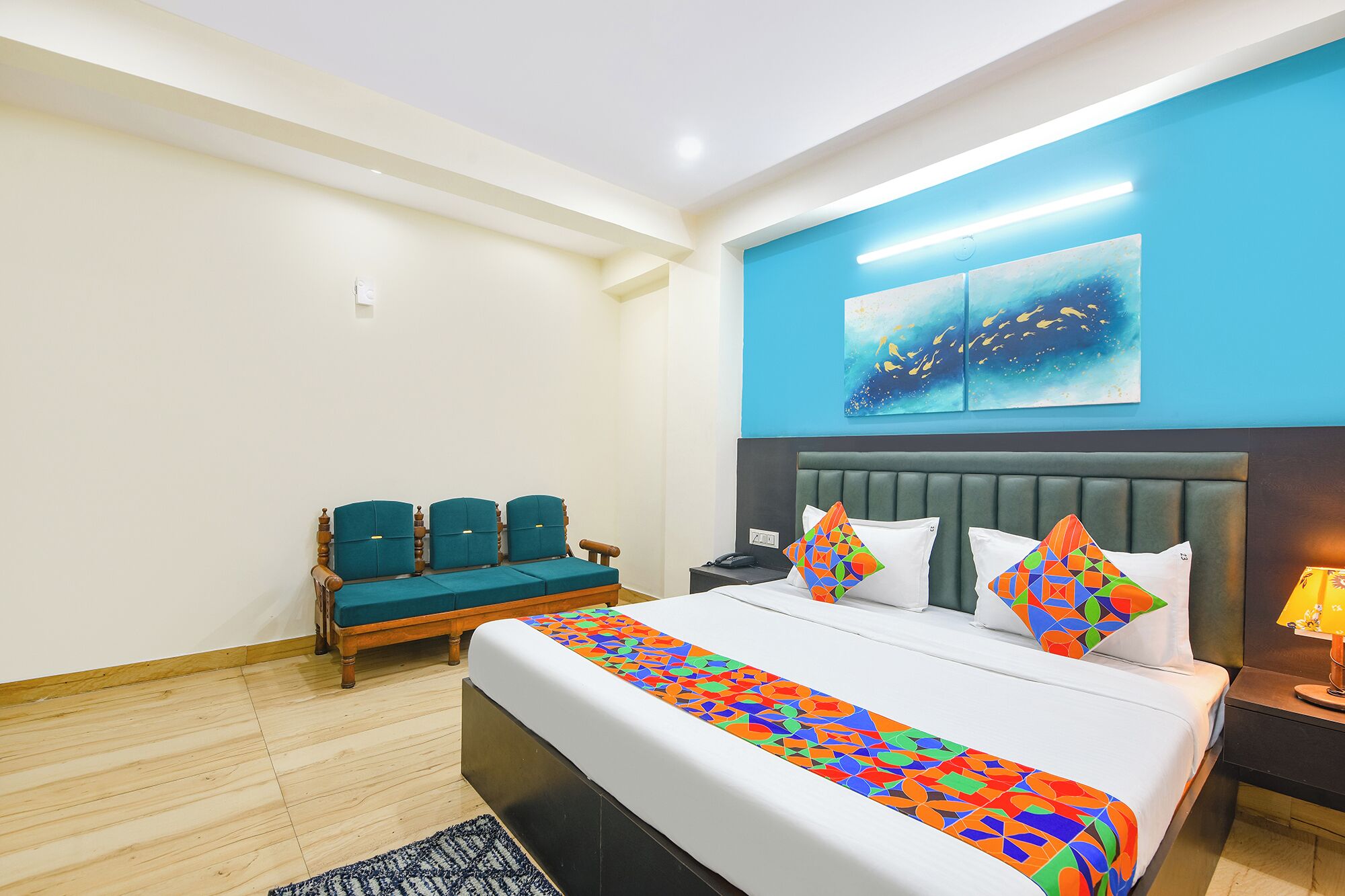 Una camera d'albergo con un letto, due sedie, un comodino e un quadro appeso al muro.