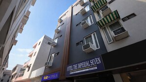 Een hotel met meerdere verdiepingen, balkons, airconditioners en een bord met de tekst 'Hotel The Imperial Seven'.