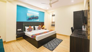 Een moderne hotelkamer met een bed, nachtkastjes, een plafondventilator, een televisie en een badkamer met douchegordijn.