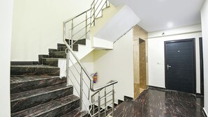 Een trap met donkere marmeren treden en metalen leuningen, die leidt naar een kamer met een deur waarop '407' staat.