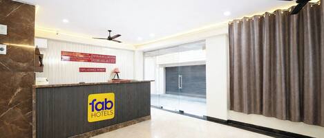 A hotel reception area with a check-in counter, a ceiling fan, and a view of the outside.