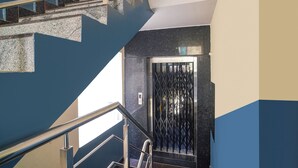 A staircase with a metal railing, a black elevator door, and a wall with a geometric pattern. - Fabhotel Sbr (Hyderabad)
