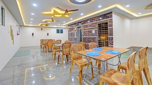 Un salón de conferencias con pared de mármol, ventiladores de techo y una gran mesa con sillas.