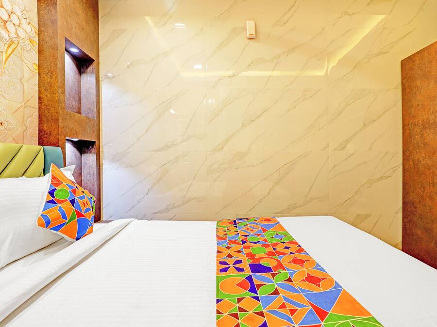 A hotel room with a bed, pillows, and a decorative wall.