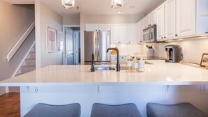 A modern kitchen with a large island, stainless steel appliances, and pendant lighting. - Mountain-front Condo Sleeps 8 + Sauna (Crested Butte)