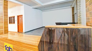 Eine moderne Hotelhalle mit Empfangstresen, Holzboden, einer Tür und einer Wand mit Ziegelmuster.