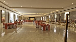 En rymlig och väl upplyst hotellobby med marmorgolv, flera sittgrupper och en central scen.
