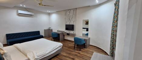 Una habitación de hotel moderna con cama, escritorio, silla, televisión y ventilador de techo.