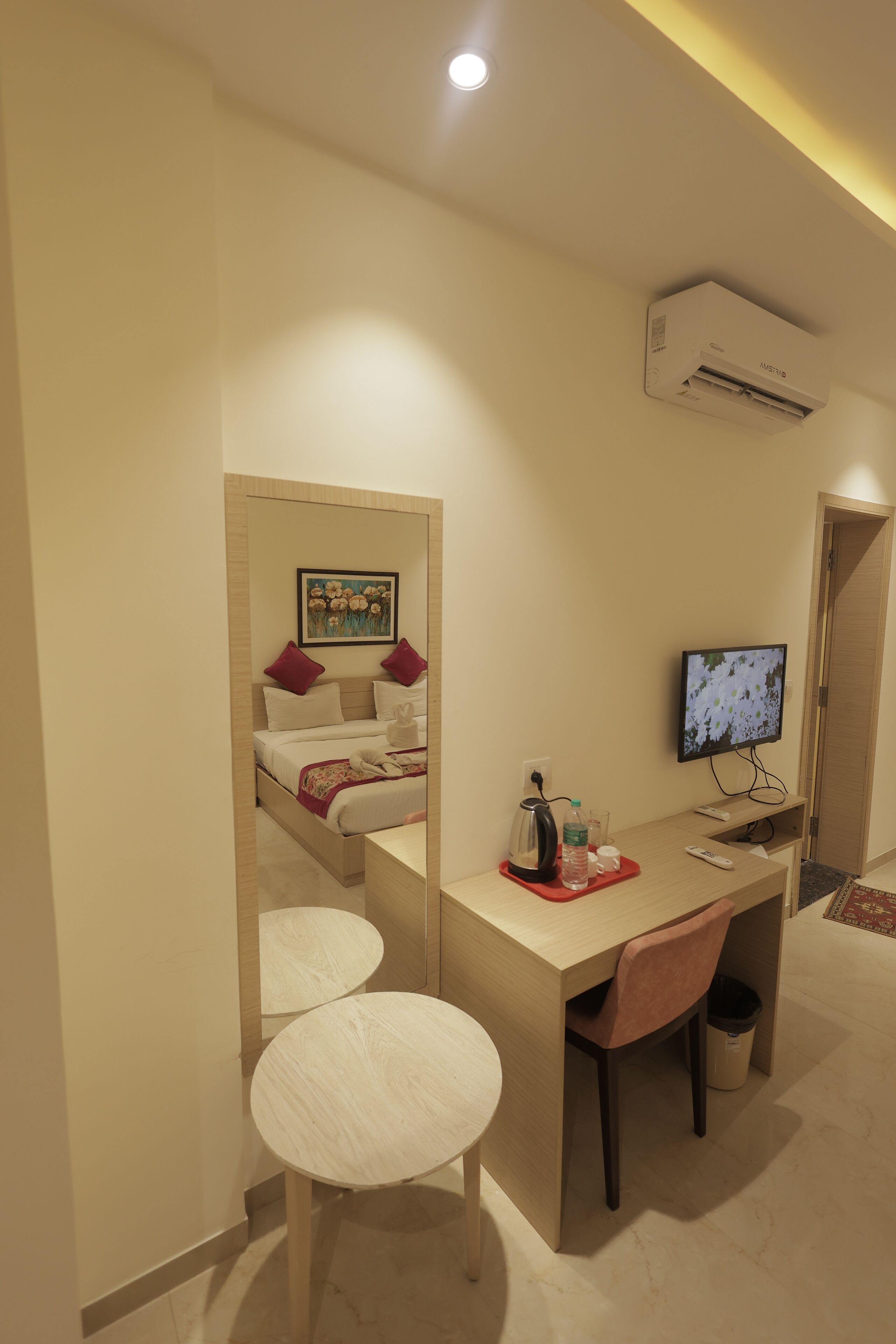 Habitación de hotel con cama, escritorio con silla, televisor y aire acondicionado.