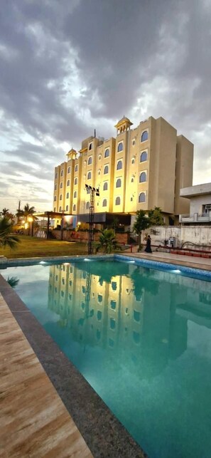 A hotel with a swimming pool, multiple floors, and a large building with a flat roof. - Hotel Grand Vasante (Bhilwara)