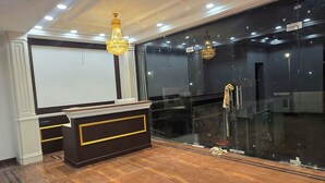A spacious room with a polished wooden floor, a reception desk, and a large black glass partition. - Hotel Parth (Faizabad)