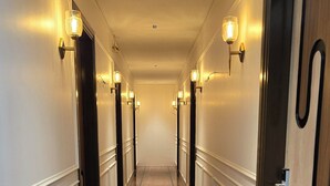 A long, well-lit hallway with polished wooden floors and doors on both sides. - Hotel Parth (Faizabad)