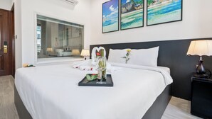 Une chambre d’hôtel avec un grand lit, une table de chevet avec une lampe, un climatiseur fixé au mur et des photos de plage encadrées.