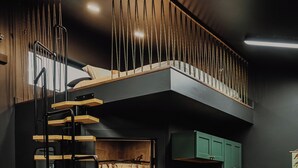 A compact, modern kitchen with a built-in refrigerator, a wooden staircase, and a bench. - Modern Mountain Mini House- studio house w/ sleeping loft Packwood with WIFI, AC (Packwood)