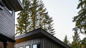 A modern building with a garage, a wooden exterior, and a gravel driveway. - Modern Mountain Mini House- studio house w/ sleeping loft Packwood with WIFI, AC (Packwood)
