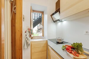 Una cucina con mobili in legno, una finestra, una pentola sul fornello e verdure fresche sul bancone.