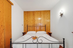 Una cama individual con cabecera de madera, ropa de cama blanca y una lámpara de pared decorativa.
