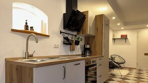A modern kitchen with a wooden countertop, white cabinets, a built-in oven, and a black television mounted above the stove. - Apartment Liesl 75sqm for max. 5 persons (Schechen)