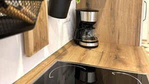 A modern kitchen with a wooden countertop, a hanging plant, a coffee maker, and a black sink. - Apartment Liesl 75sqm for max. 5 persons (Schechen)