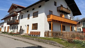 A two-story building with balconies, a wooden fence, and a bench. - Apartment Rosa 35sqm with balcony (Schechen)