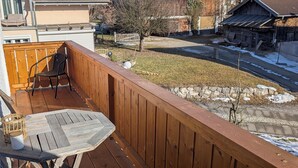 A wooden deck with a table and chairs, a view of a street with buildings, and a clear blue sky. - Apartment Rosa 35sqm with balcony (Schechen)