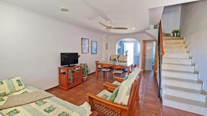 A living room with a TV, wooden furniture, a dining area, and a staircase. - El Alfar - Denia, Costa Blanca (Denia)