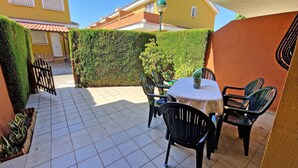 A patio area with a tiled floor, a round table with chairs, a potted plant, and a green hedge. - El Alfar - Denia, Costa Blanca (Denia)