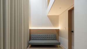 Un interior moderno con un sofá, una puerta de madera y un elemento decorativo iluminado en la pared.