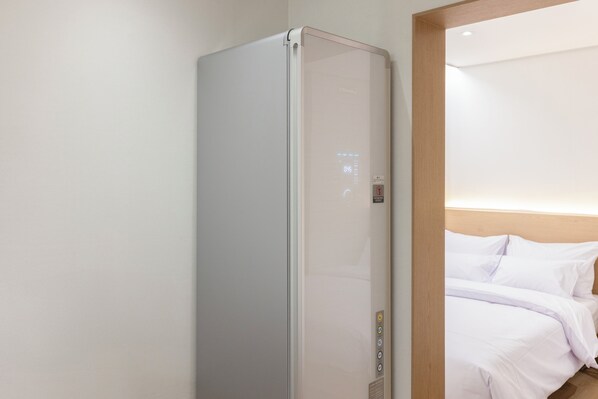 A hotel room with a modern, minimalist design, featuring a bed with white linens and a built-in heater. - US Hotel Seoul Gangseo Hwagok (Seoul)