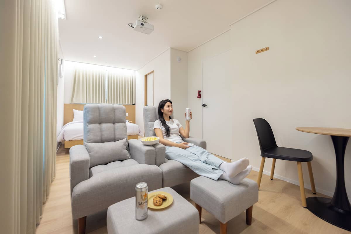 Ein modernes Hotelzimmer mit einer Couch, einem kleinen Tisch und einem Bett.