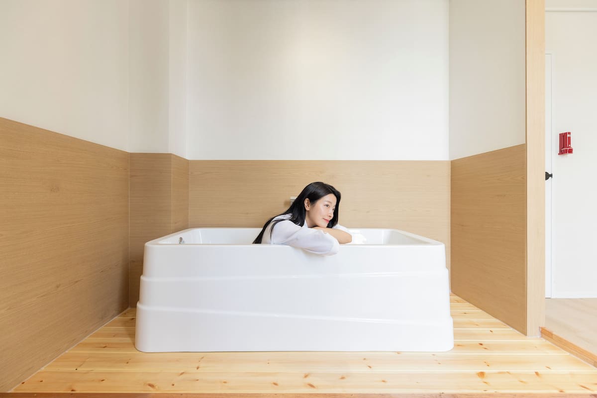 Ein modernes Badezimmer mit einer grossen Badewanne, Holzboden und einer Holzvertäfelung.
