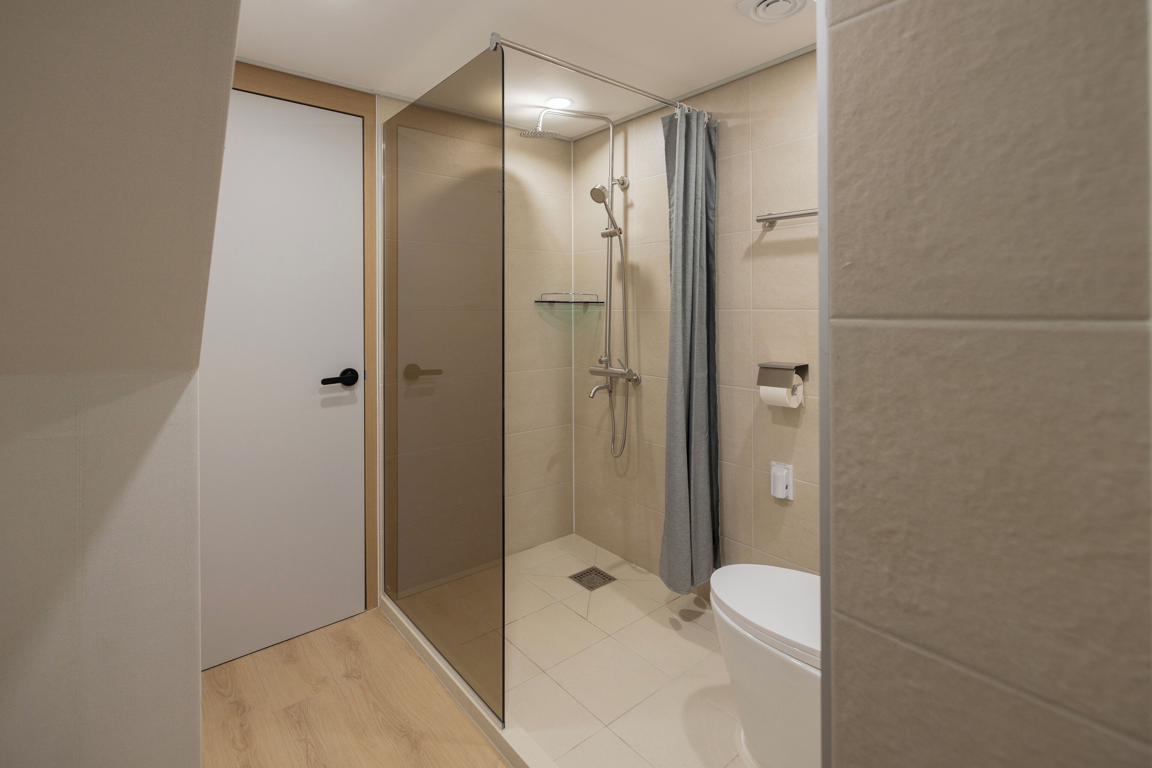 A modern bathroom with a glass-enclosed shower, a toilet, and a towel rack.