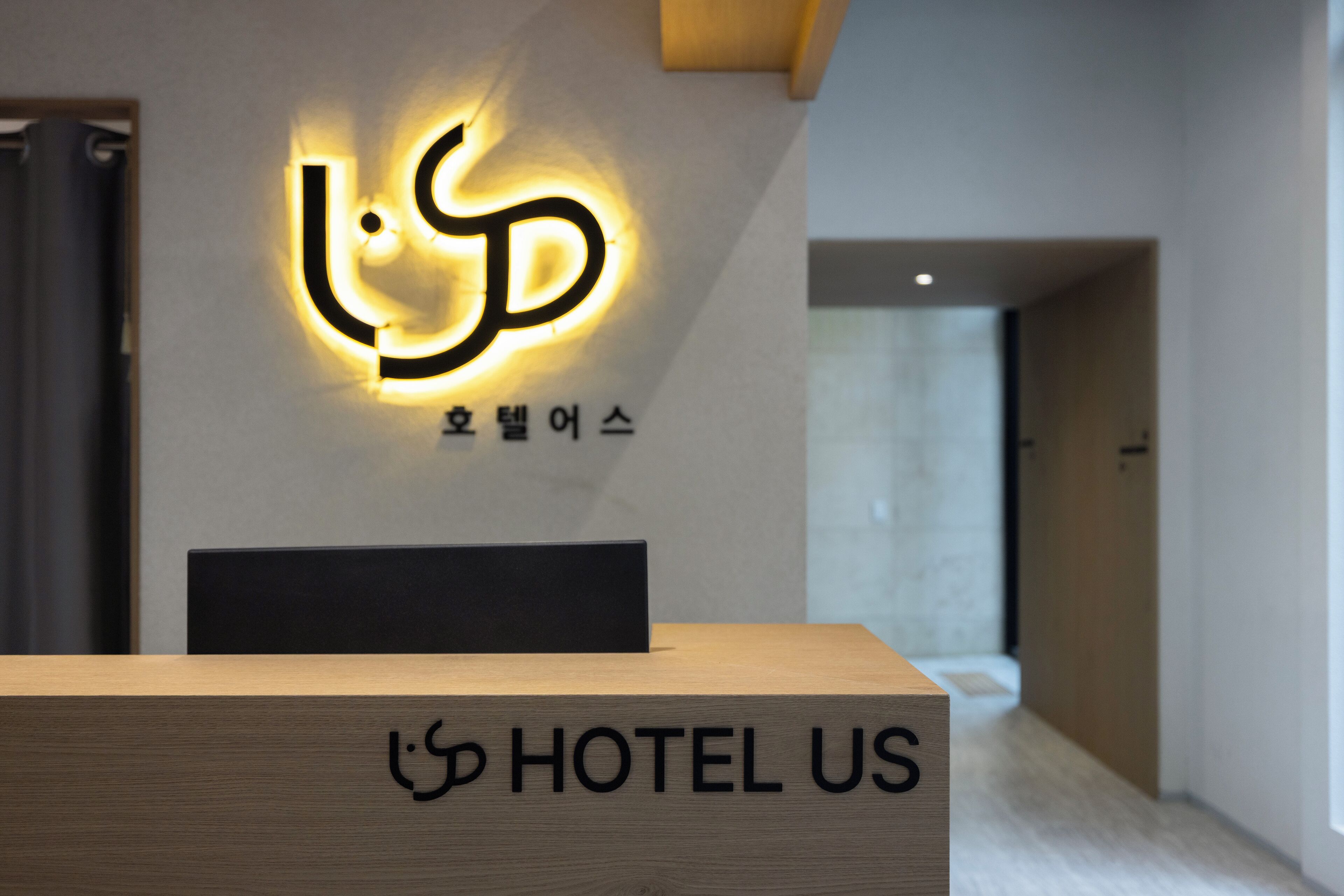 A hotel reception desk with a modern sign and a wooden counter displaying the hotel name.