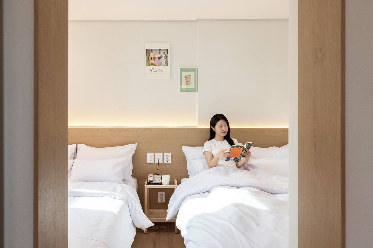 Ein Hotelzimmer mit zwei Betten, einem Nachttisch mit Lampe und einem Wandbild.