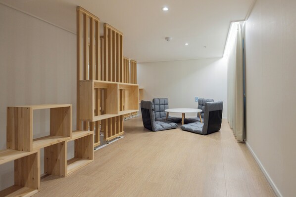 A room with a wooden bookshelf, a round table with two chairs, and a large window with curtains. - US Hotel Seoul Gangseo Hwagok (Seoul)