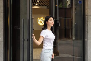 A woman standing at the entrance of a hotel with a neon sign in the background. - US Hotel Seoul Gangseo Hwagok (Seoul)