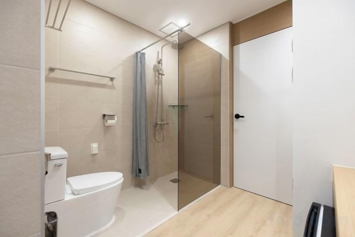Un baño moderno con inodoro, ducha y cabina de ducha con mampara de vidrio.