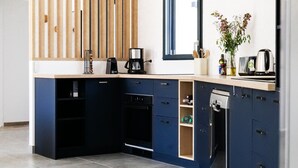 Une cuisine moderne avec des meubles de couleur bleu foncé, un four encastré, une machine à café et un lave-vaisselle.