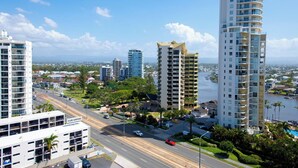 A high-rise building with multiple balconies, a marina with boats, and a clear blue sky. - Solnamara Apartments (Burleigh Heads)