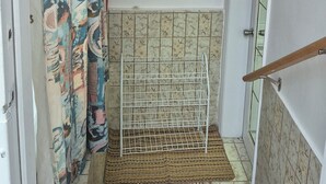 Eine enge Treppe mit einem gemusterten Teppich, einem Metallregal und einem Regal mit Pflanzen.