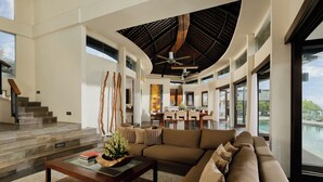 A spacious living area with a large sofa, a coffee table, and a view of a pool.
