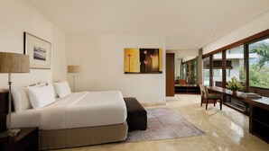 A modern bedroom with a large bed, a desk, and a view of the outdoors.
