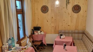 A cozy dining area with checkered tablecloths, wooden walls, and a rustic ceiling. - Drachenhaus Urban Villa (Brasov)