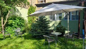 Une terrasse avec quatre chaises en métal et une table, un grand parasol et un petit sapin de Noël.
