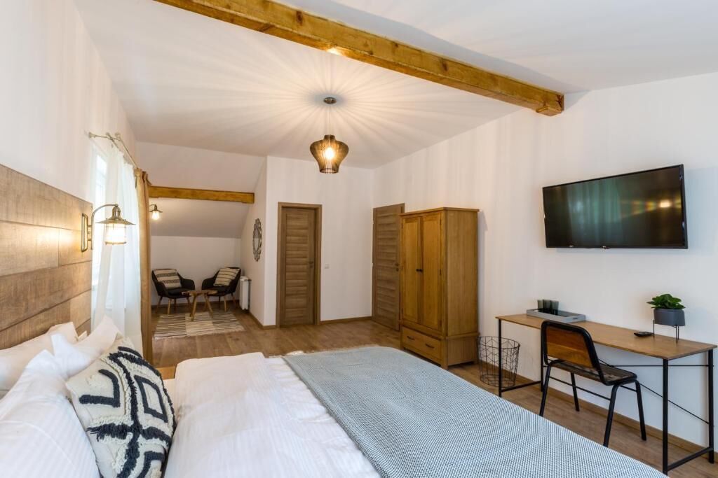 A bedroom with a bed, a desk, a chair, a TV, and a wardrobe.