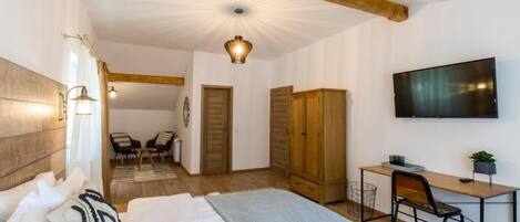 A bedroom with a bed, a desk, a chair, a TV, and a wardrobe.