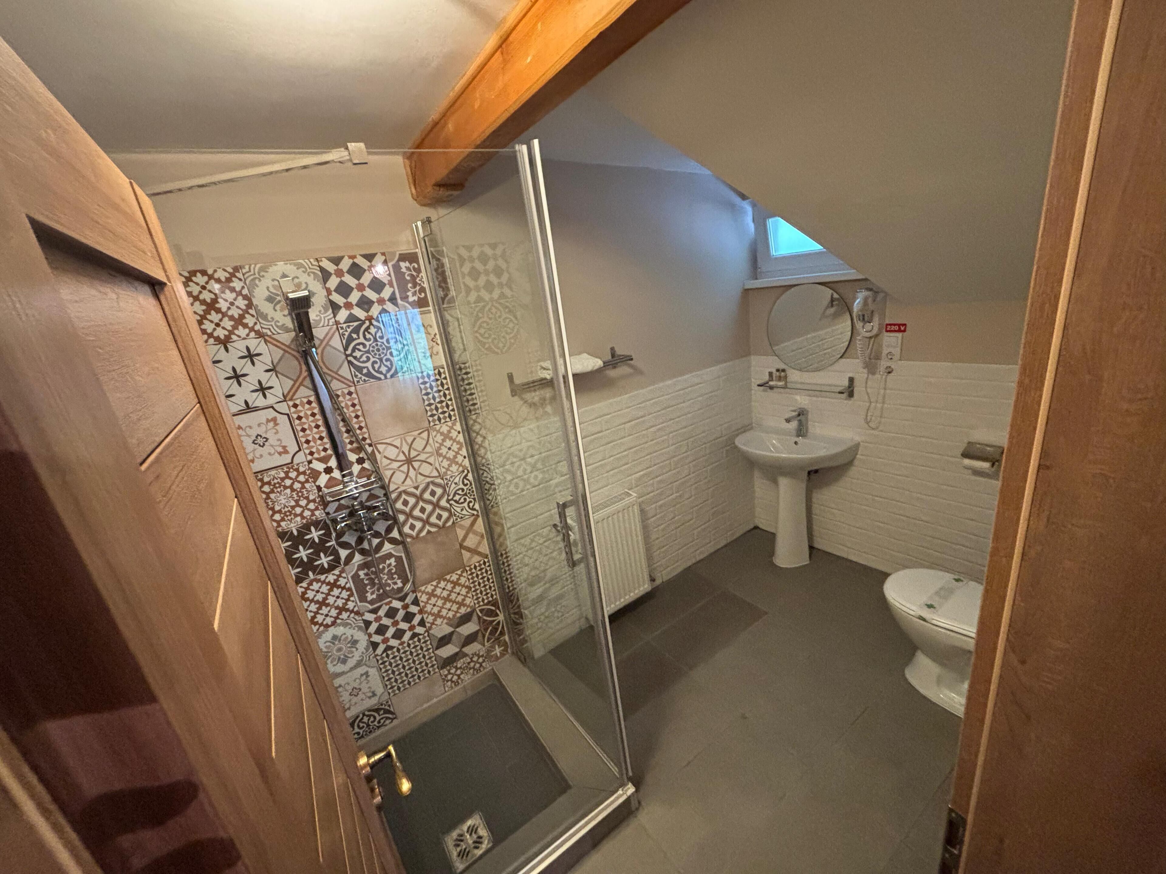 Et badeværelse med bruser, håndvask og toilet.