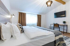 Un dormitorio moderno con una cama grande, un escritorio y un televisor.